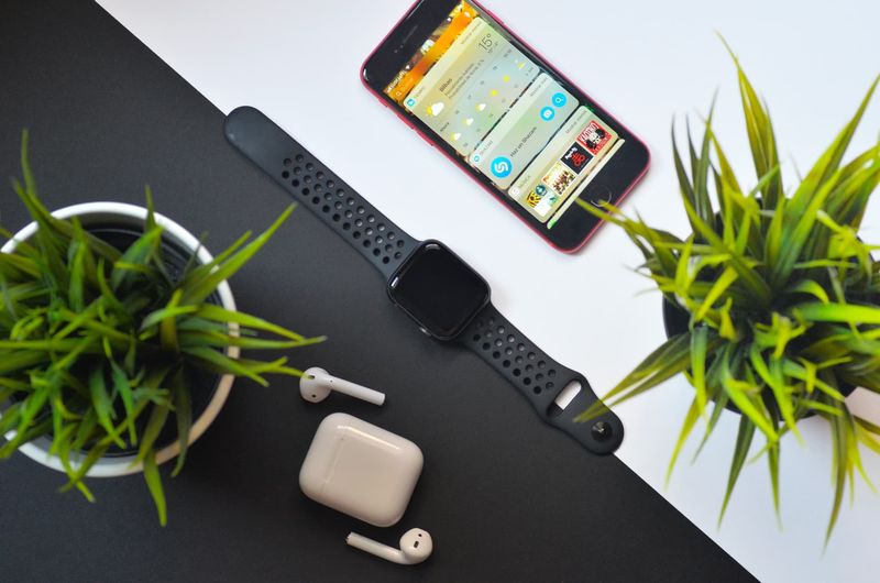 Apple Watch auf einem Tisch mit einem iPhone und AirPods in der Nähe