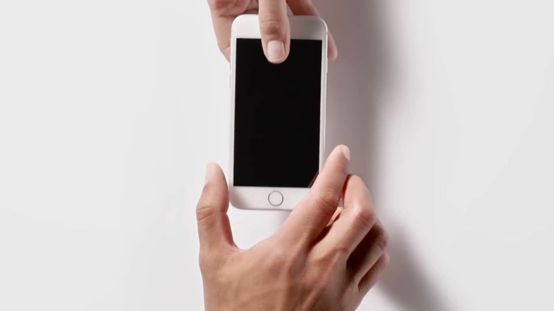 Szene aus der Ap-in-Werbung, in der eine männliche Hand einem anderen Mann ein iPhone 5s überreicht