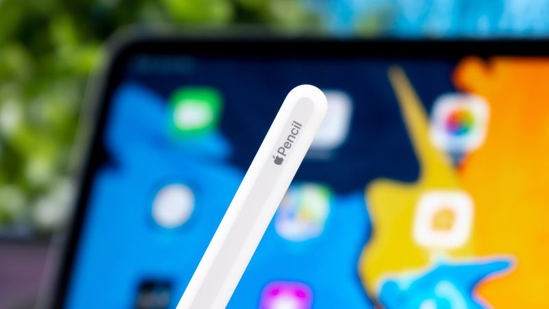 Nahaufnahme, die das Ende des Apple Pencil mit Branding zeigt, mit einem verschwommenen iPad Pro im Hintergrund