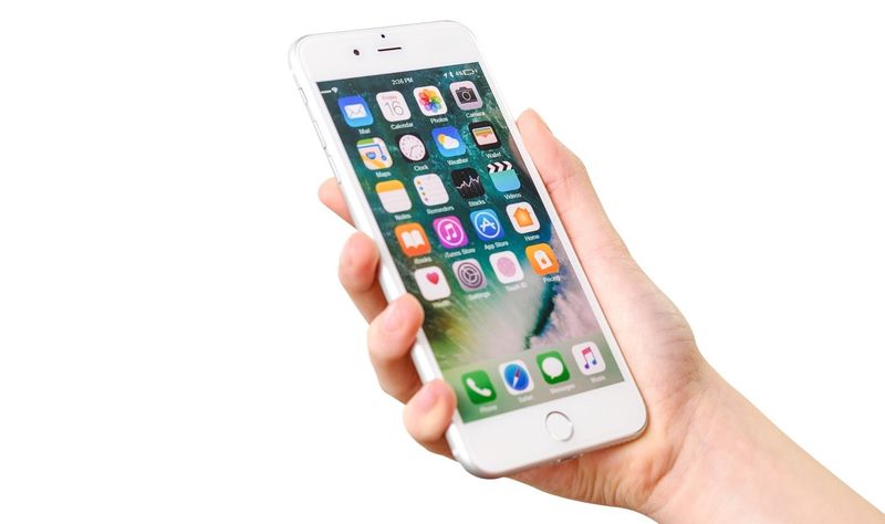 Hand, die silbernes iPhone auf einem weißen Hintergrund hält