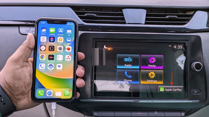 Apple CarPlay auf dem Armaturenbrett des Autos mit verbundenem iPhone in der Hand